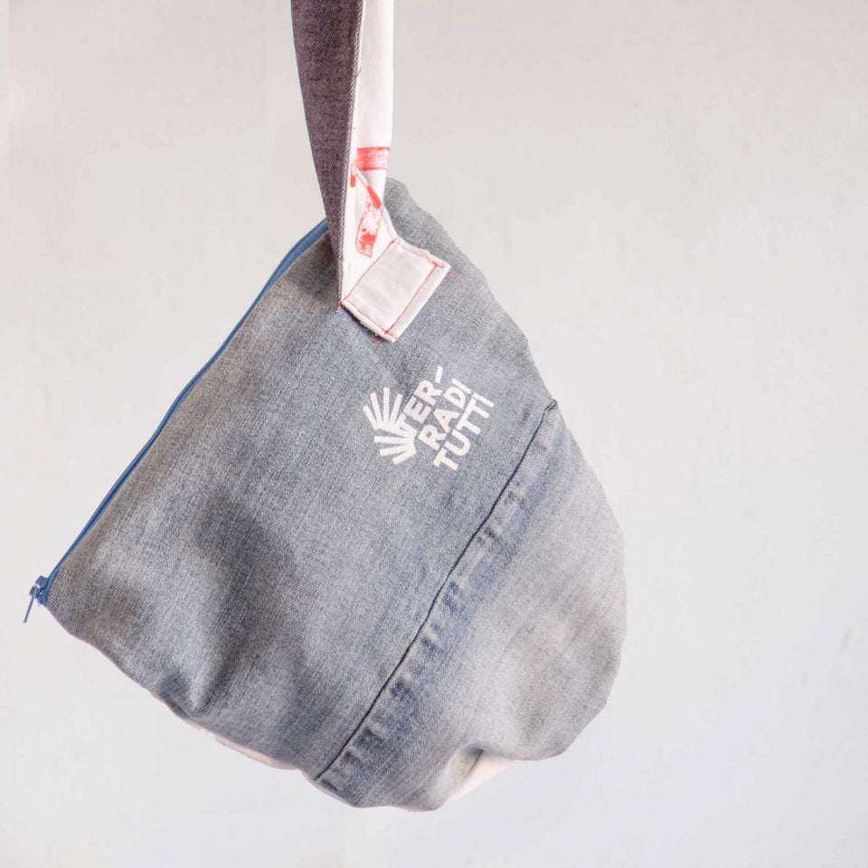 Borsina con tracolla fatta artigianalmente con jeans e tessuto di recupero, con marchio di Terra di Tutti, cooperativa sociale di Lucca.